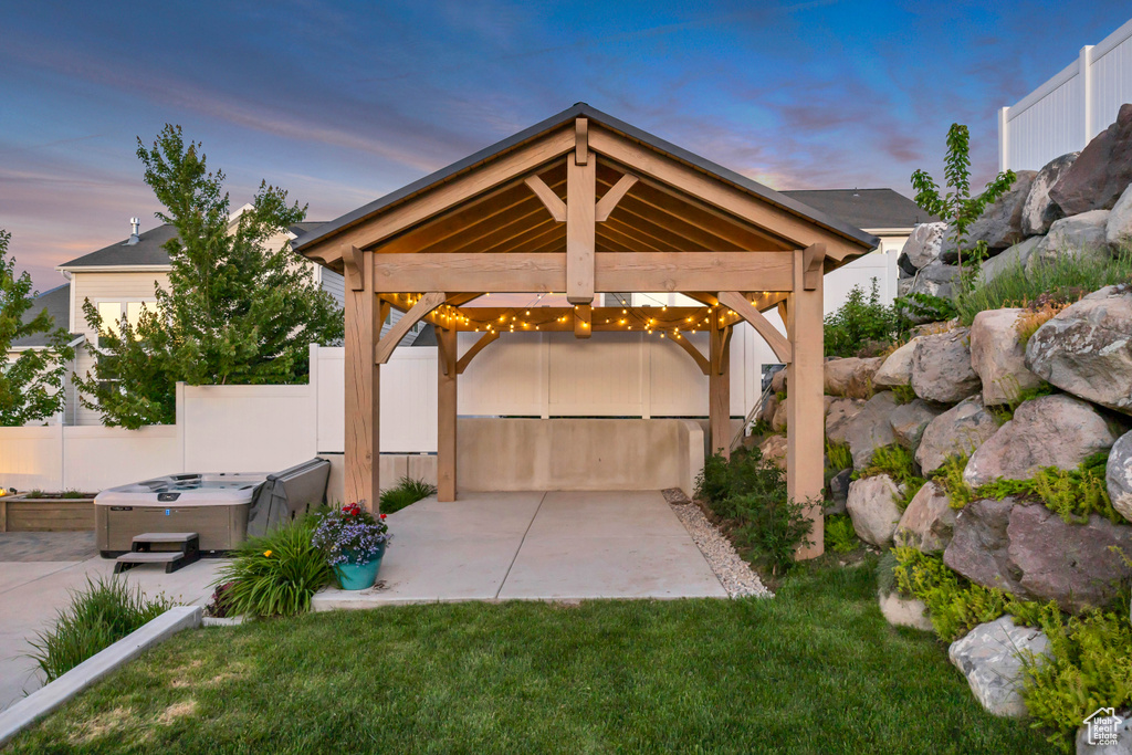 Patio terrace at dusk featuring a hot tub, a gazebo, and a patio