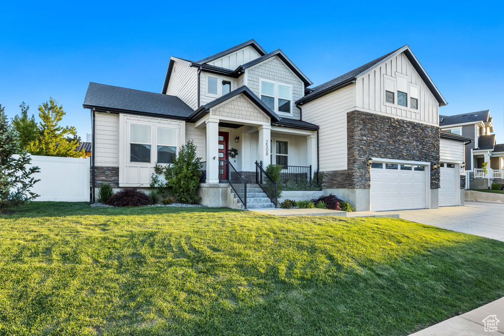 Craftsman-style home with board and batten siding, stone siding, an attached garage, and driveway