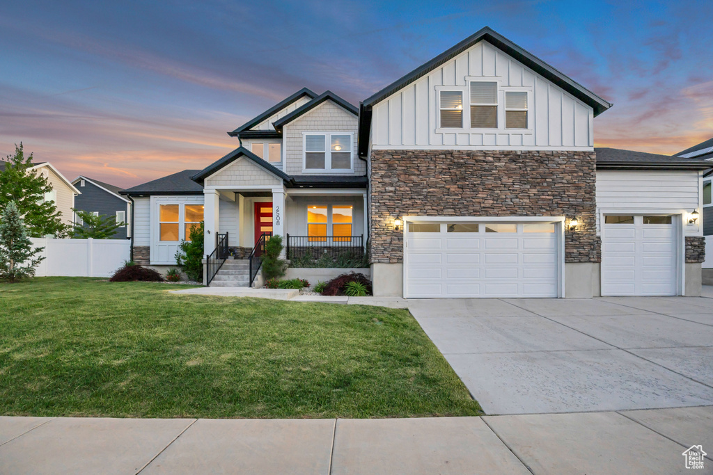 View of front of home with stone siding, board and batten siding, driveway, and covered porch