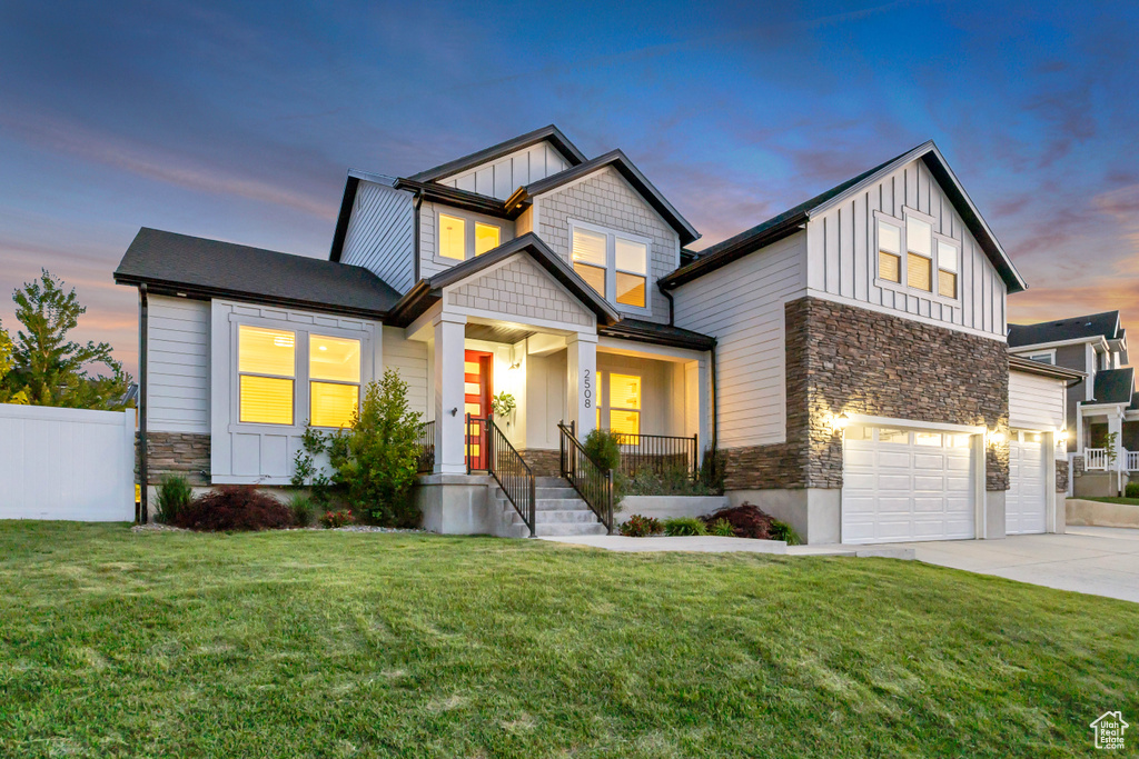 Craftsman-style home with stone siding, board and batten siding, a garage, and driveway