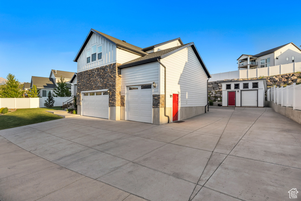 View of side of home with stone siding, driveway, board and batten siding, and an attached garage
