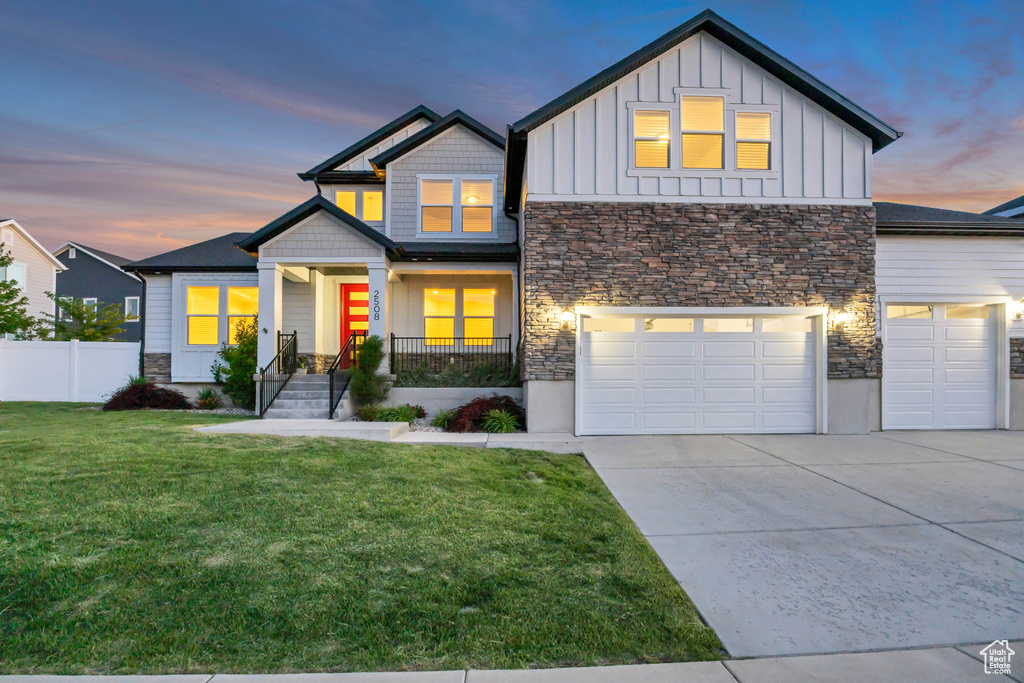 View of front of property featuring stone siding, board and batten siding, driveway, and a garage
