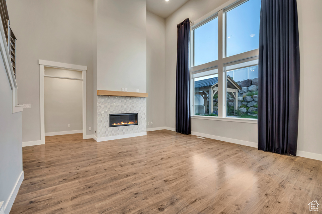 Unfurnished living room featuring a high ceiling, wood finished floors, and a fireplace