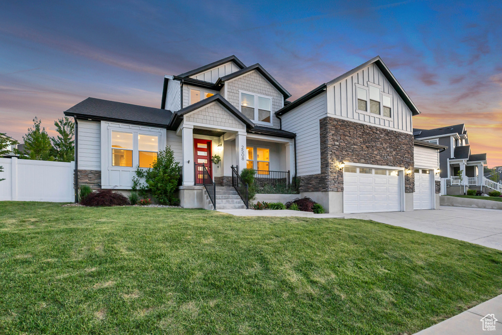 View of front facade with stone siding, board and batten siding, concrete driveway, and a garage