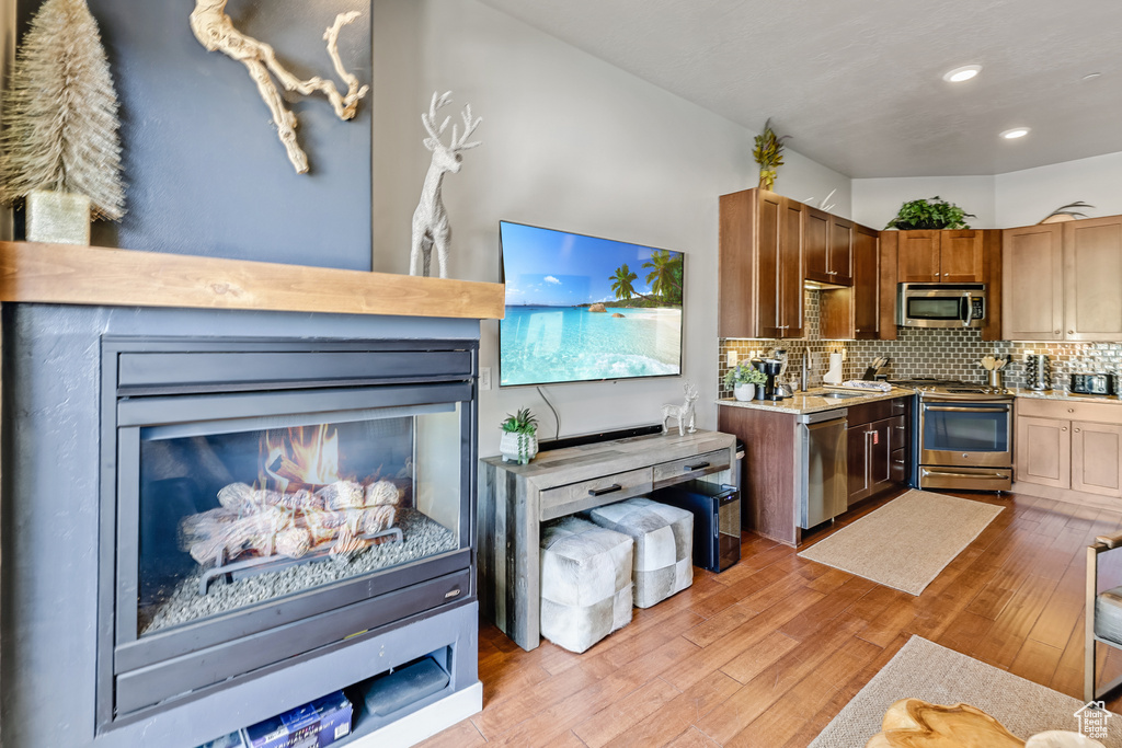 Kitchen with appliances with stainless steel finishes, light countertops, light wood finished floors, decorative backsplash, and recessed lighting