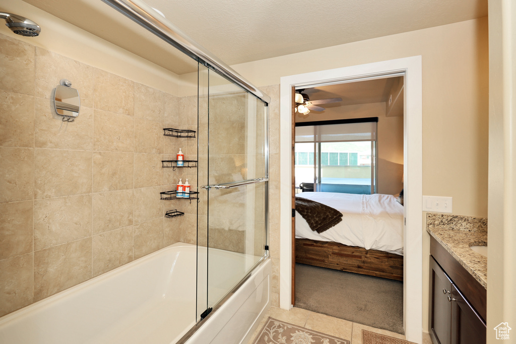 Bathroom with vanity, ensuite bathroom, enclosed tub / shower combo, ceiling fan, and tile patterned flooring