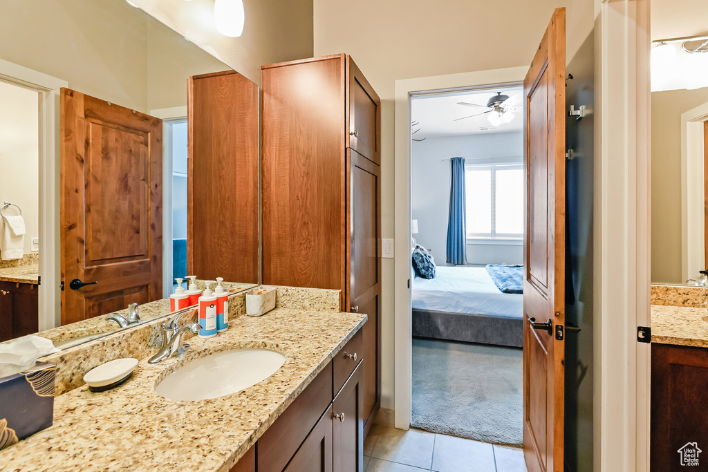 Ensuite bathroom featuring vanity, tile patterned floors, and a ceiling fan