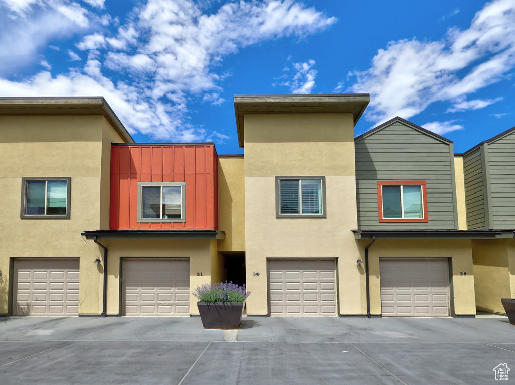 View of property with an attached garage, driveway, and stucco siding