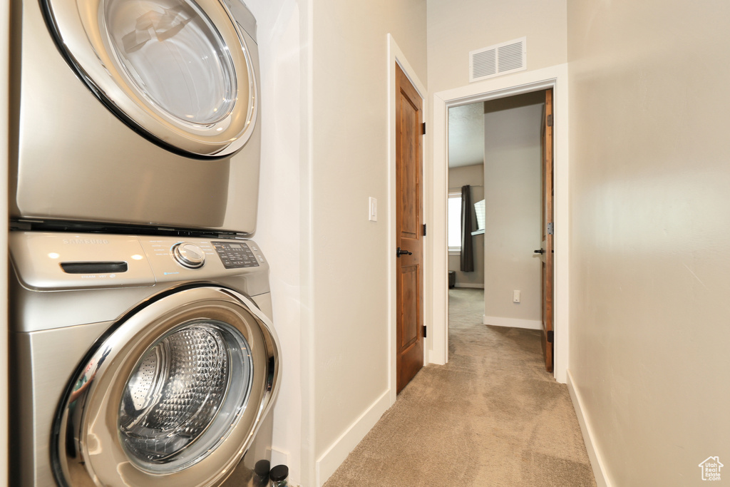 Laundry room featuring stacked washer / drying machine and carpet flooring