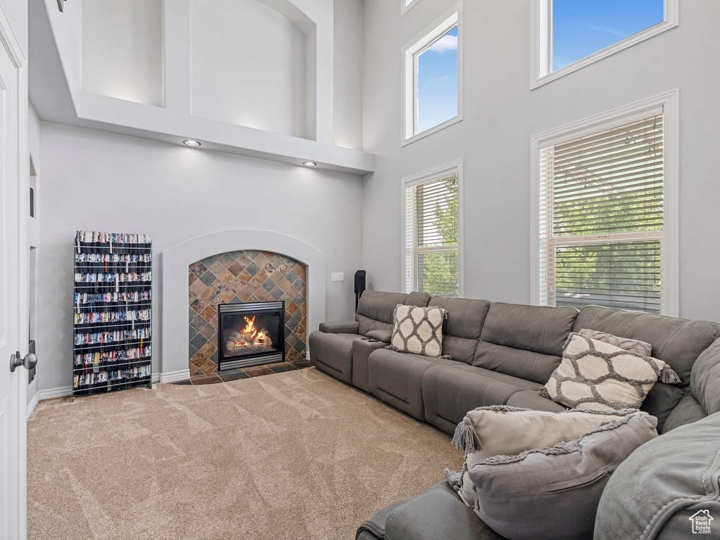 Carpeted living area with a high ceiling and a tiled fireplace