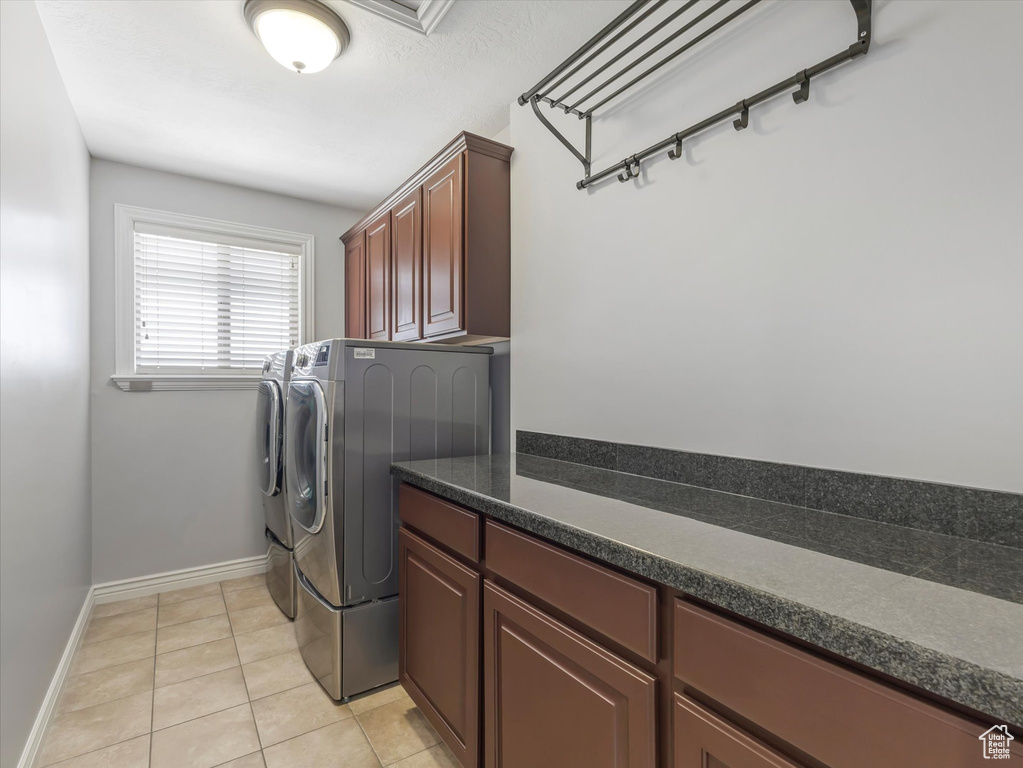 Laundry area featuring independent washer and dryer, cabinet space, and light tile patterned floors