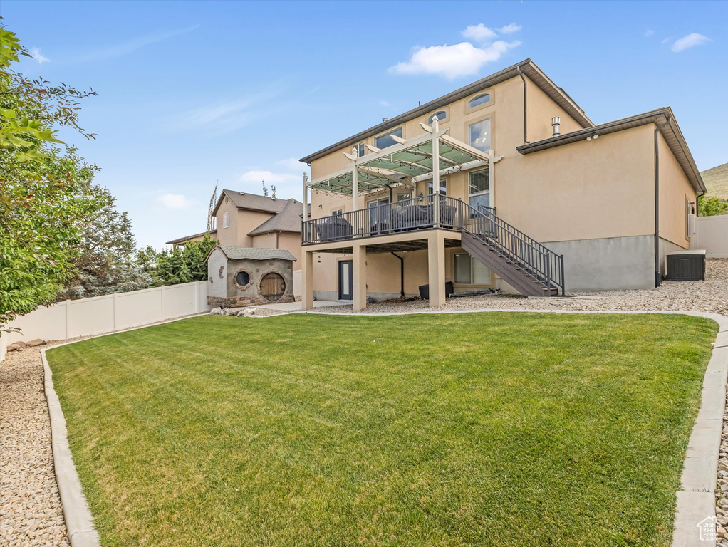 Back of property featuring stairway, a deck, a fenced backyard, stucco siding, and a storage shed