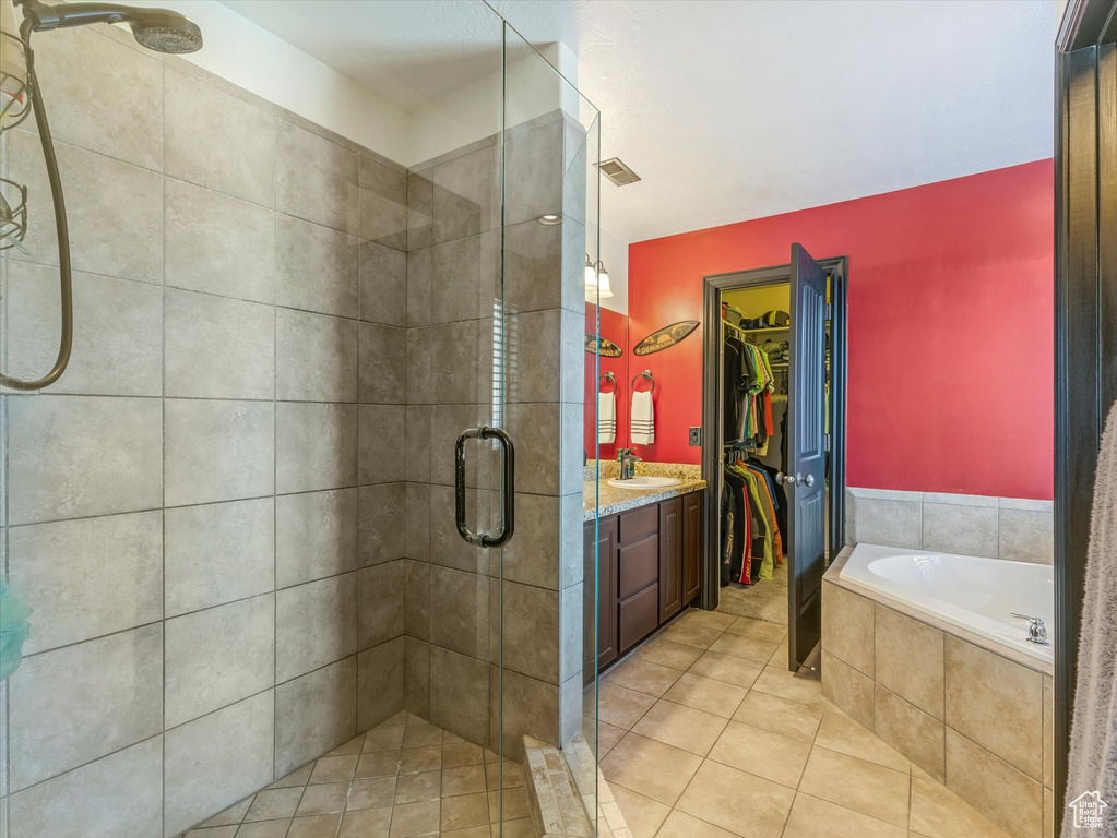 Full bath featuring a stall shower, a spacious closet, a bath, vanity, and tile patterned flooring
