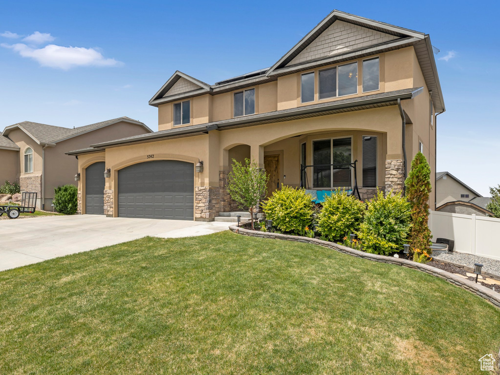 View of front facade with stucco siding, stone siding, concrete driveway, and a garage