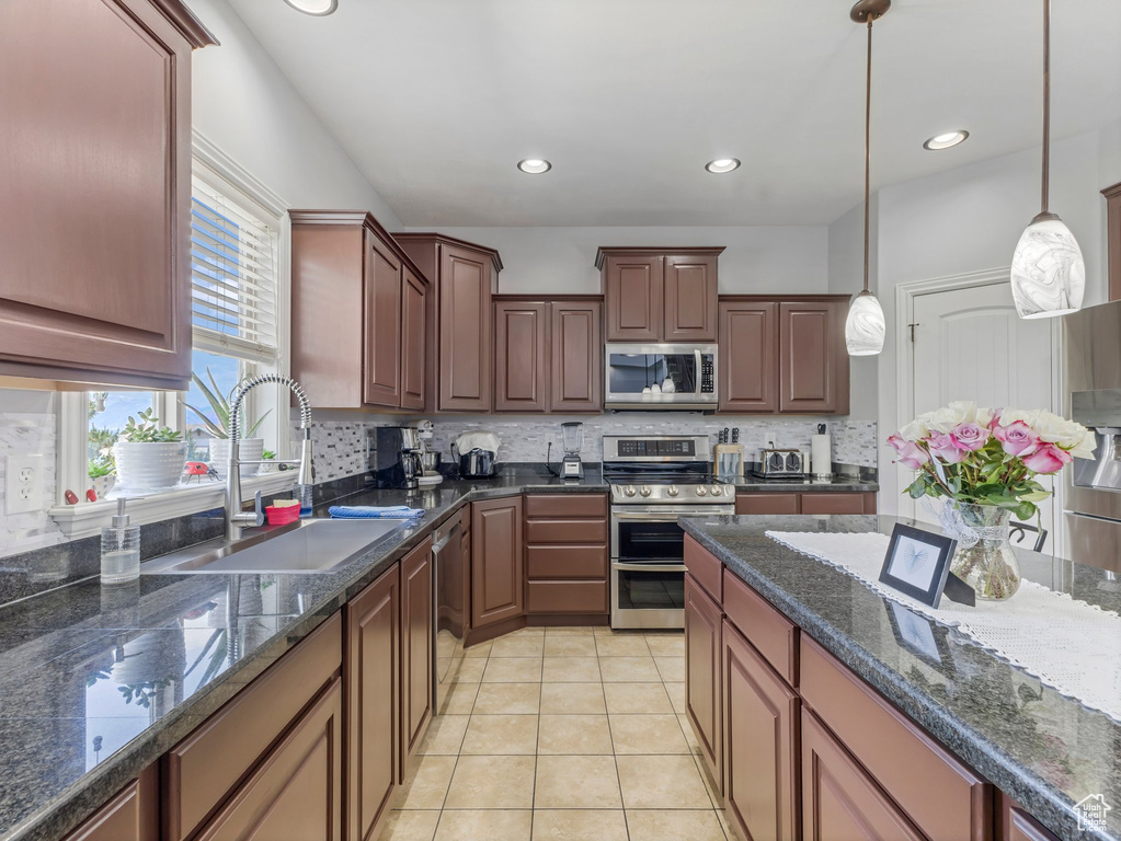 Kitchen featuring stainless steel appliances, tasteful backsplash, pendant lighting, light tile patterned floors, and recessed lighting