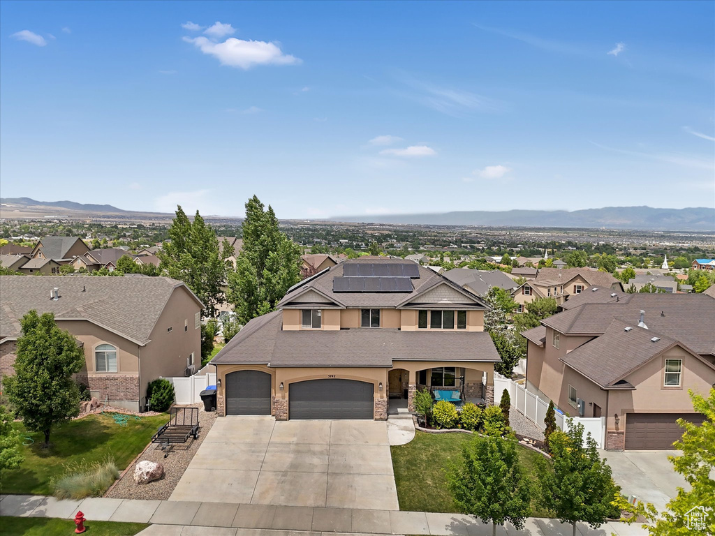 View of front of house featuring a residential view, concrete driveway, roof mounted solar panels, and covered porch