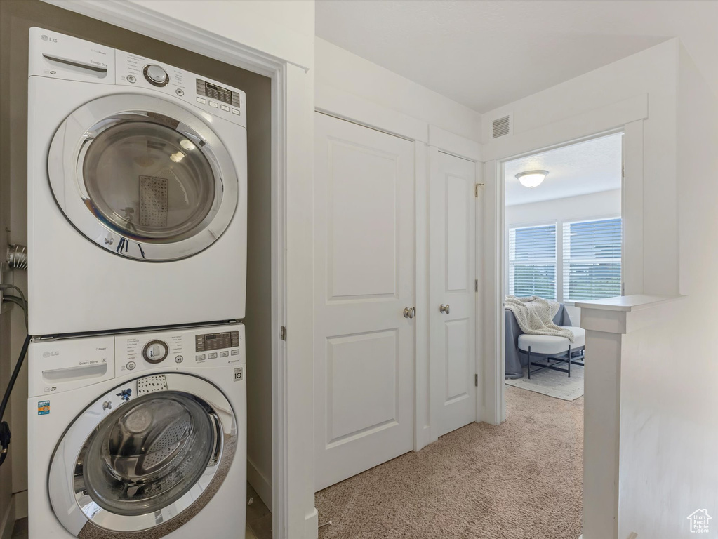 Washroom with estacked washer and dryer and carpet