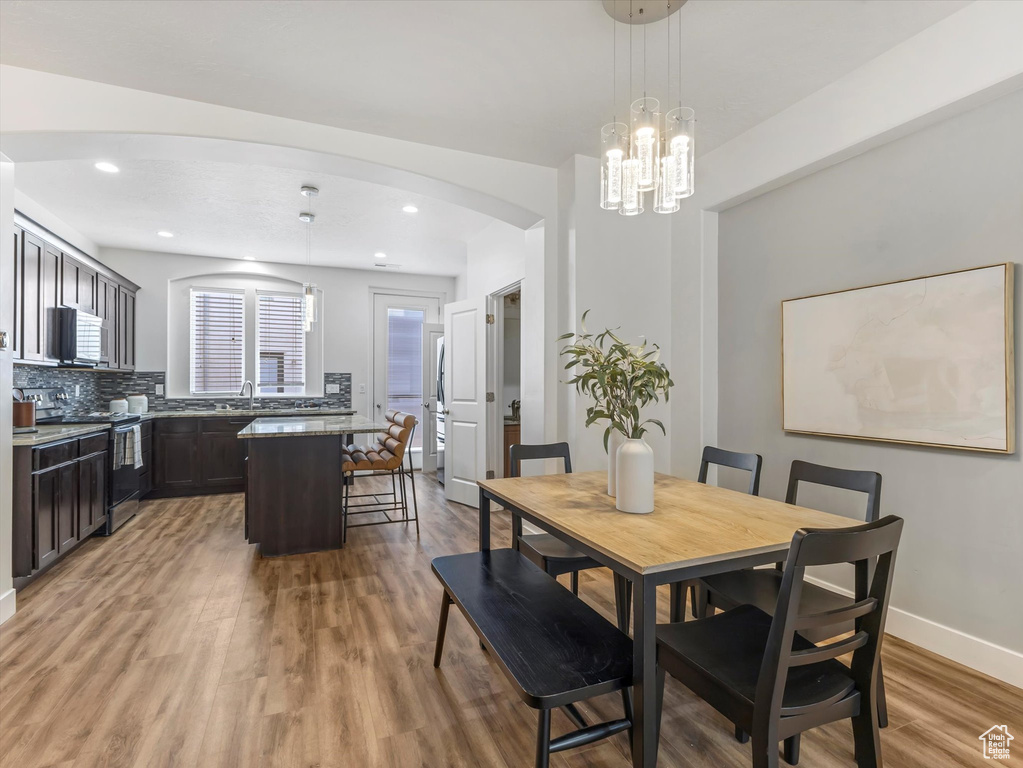 Dining area featuring light wood-style floors, arched walkways, recessed lighting, and a chandelier