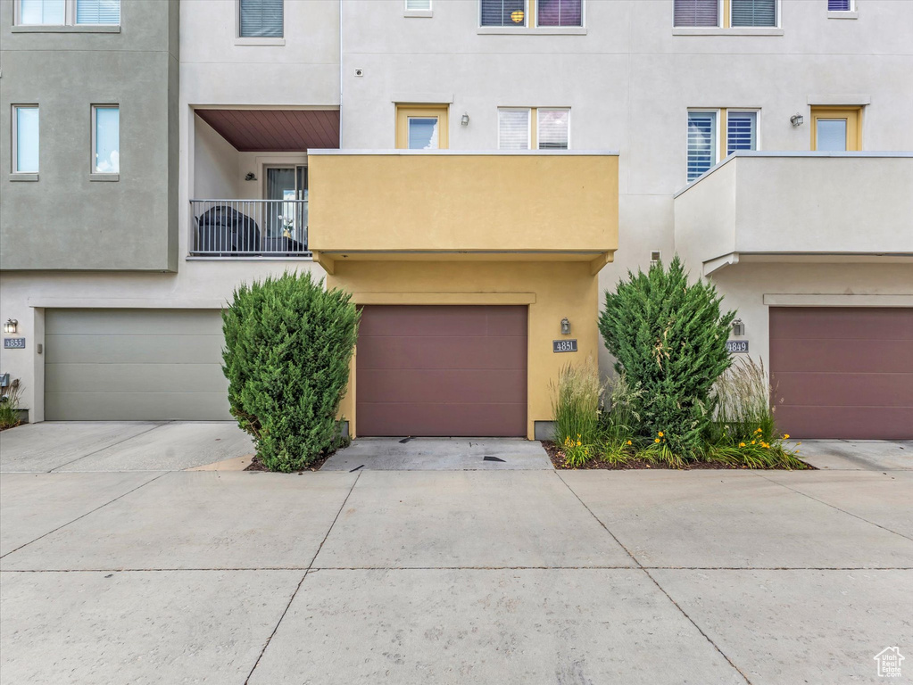 View of front of property featuring an attached garage, stucco siding, and concrete driveway