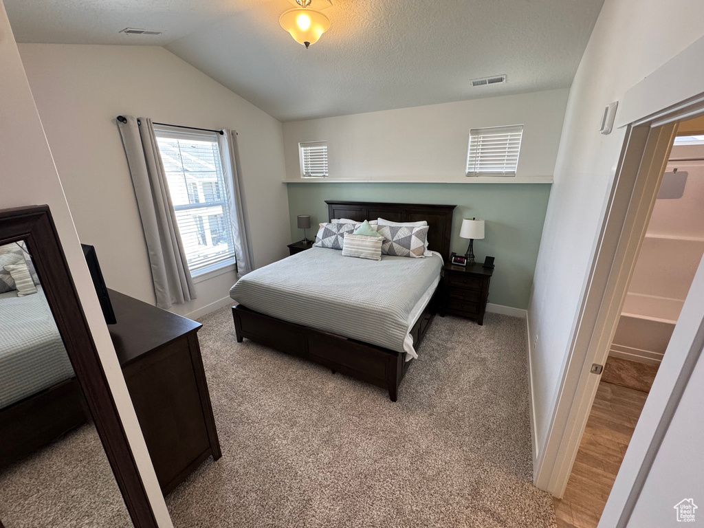 Bedroom featuring vaulted ceiling and light carpet