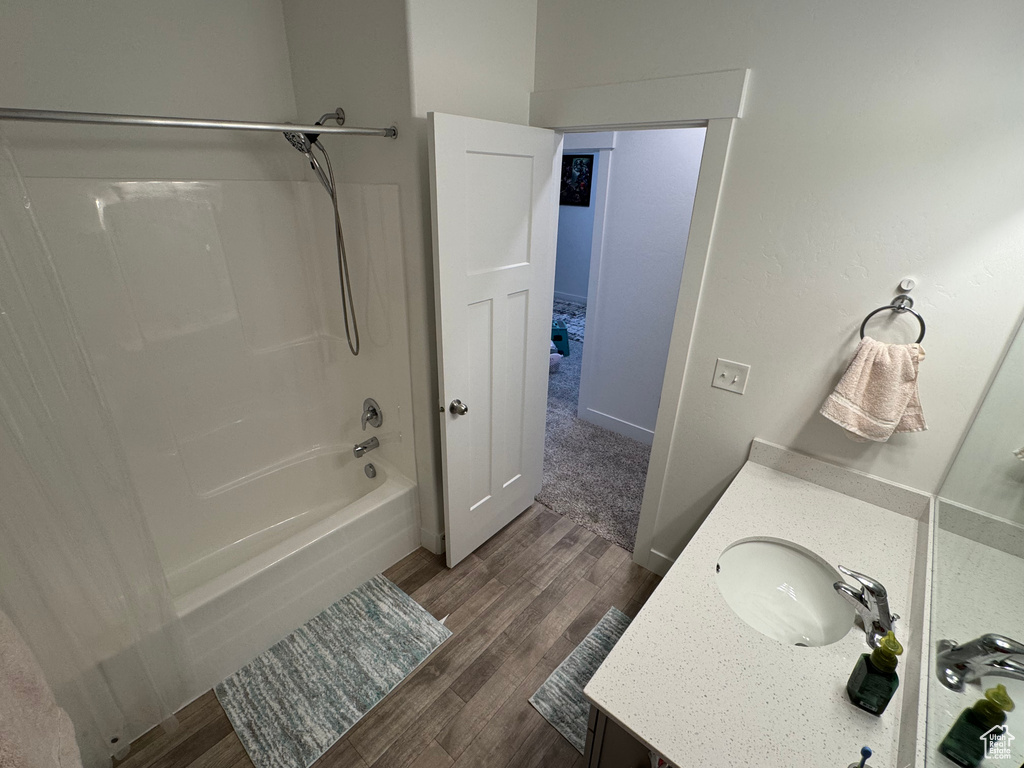 Bathroom with vanity, wood finished floors, and bathtub / shower combination