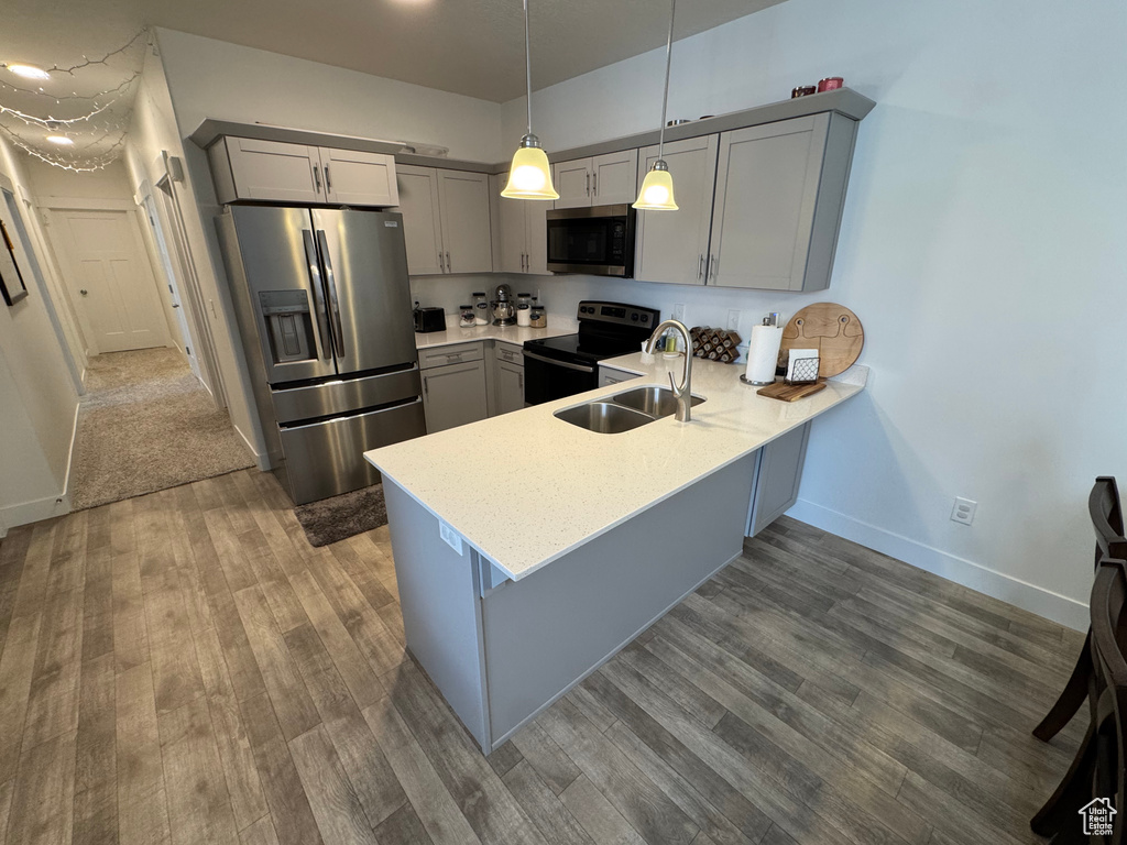 Kitchen featuring stainless steel appliances, gray cabinets, a peninsula, and dark wood finished floors
