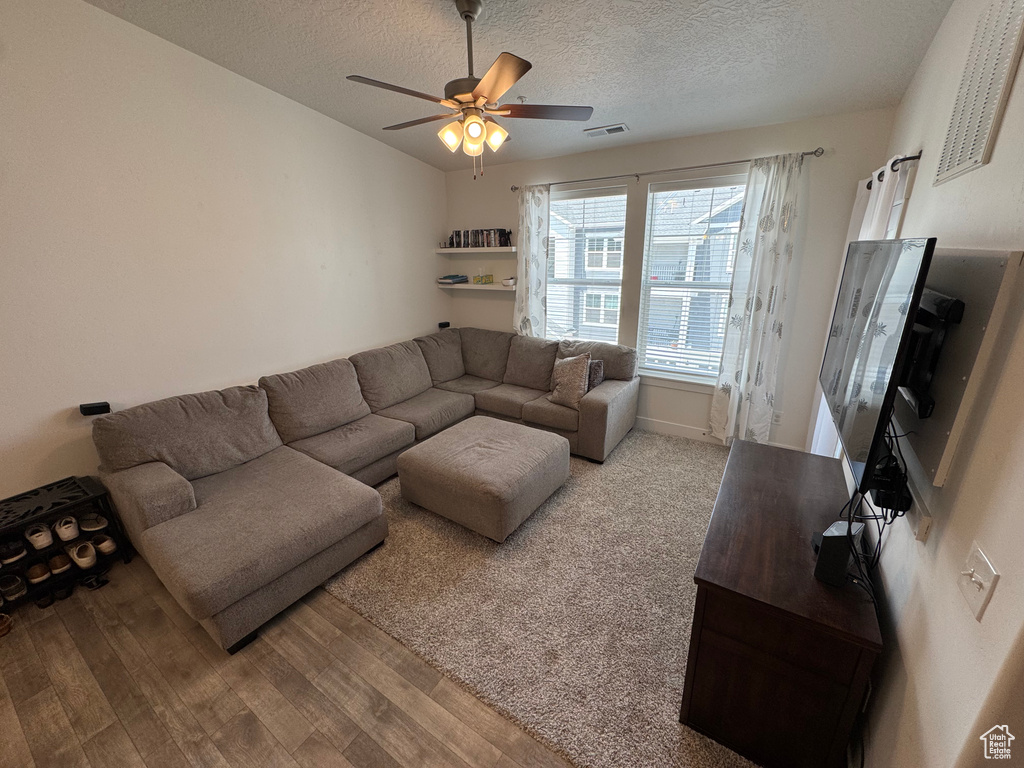 Living area featuring wood finished floors, ceiling fan, and a textured ceiling