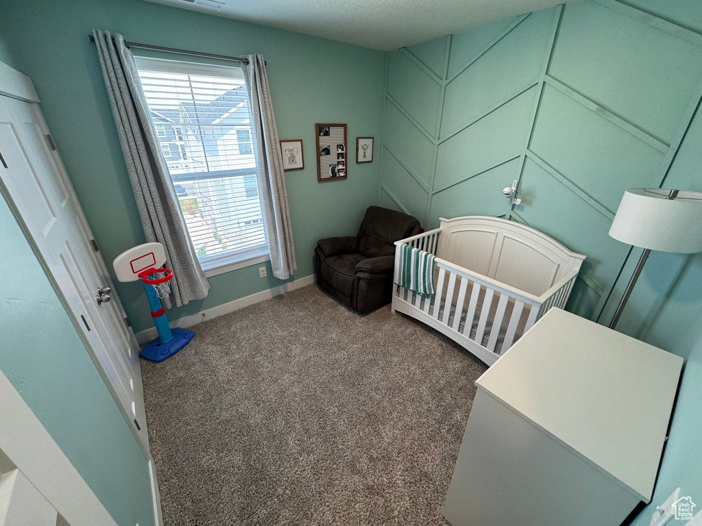 Bedroom with multiple windows, carpet floors, and a crib