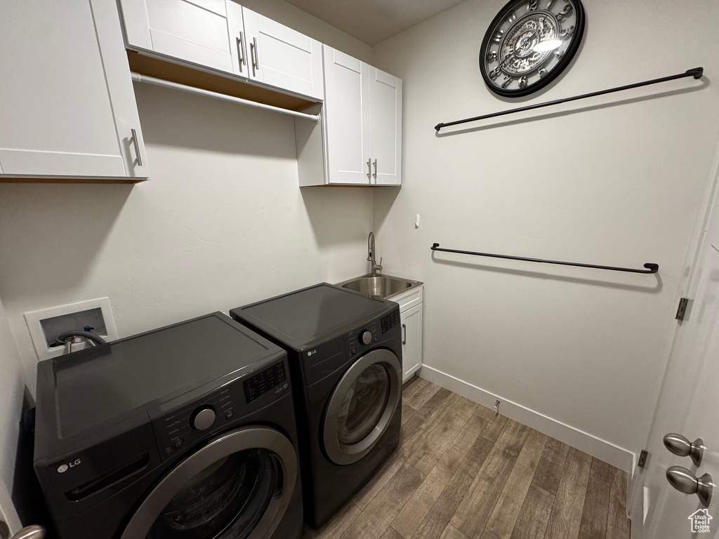 Laundry area featuring washer and clothes dryer, wood finished floors, and cabinet space