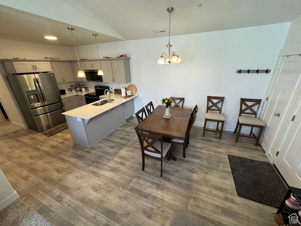 Dining space featuring vaulted ceiling, wood finished floors, and a chandelier