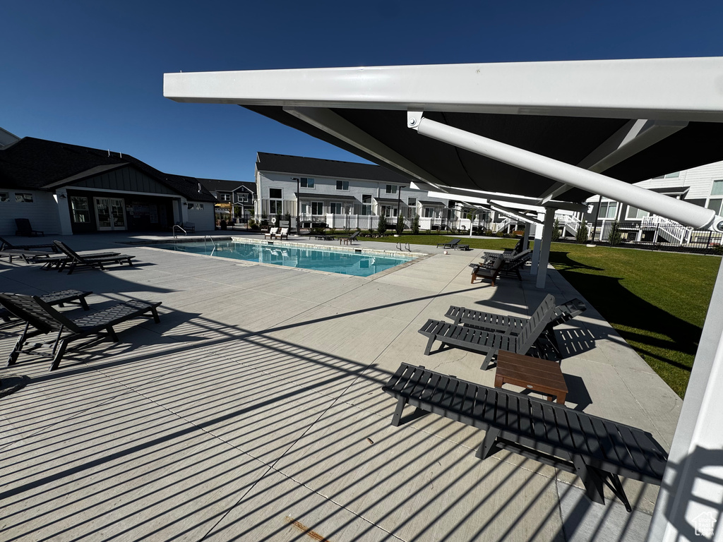 Community pool featuring a patio and a lawn