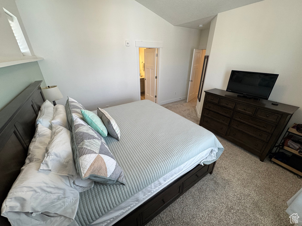 Bedroom featuring lofted ceiling and light colored carpet
