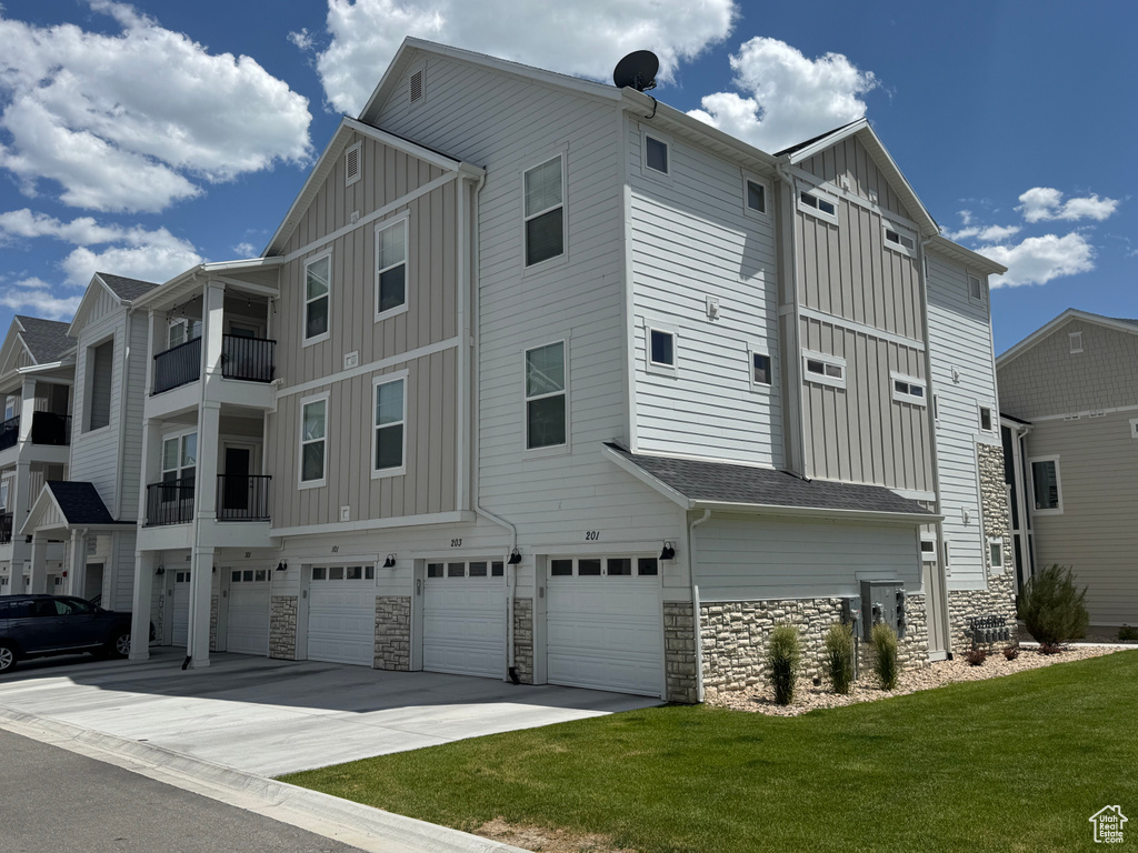 View of side of property with board and batten siding, an attached garage, and stone siding