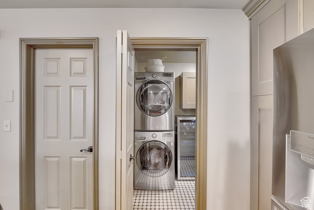 Washroom featuring estacked washer and dryer, wine cooler, and cabinet space