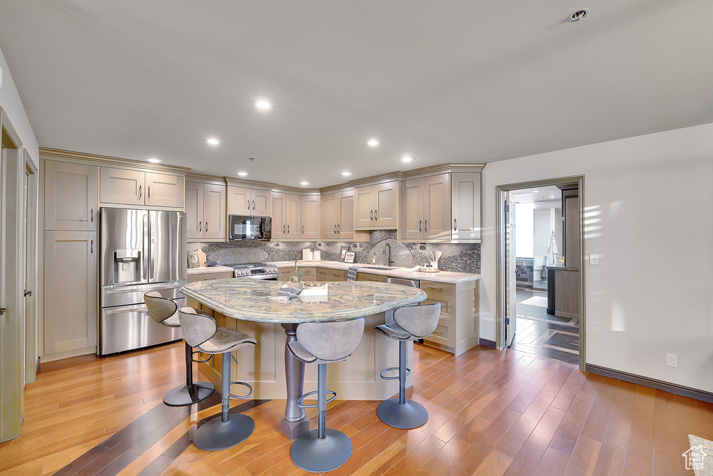 Kitchen with stainless steel appliances, backsplash, a breakfast bar area, gray cabinets, and recessed lighting