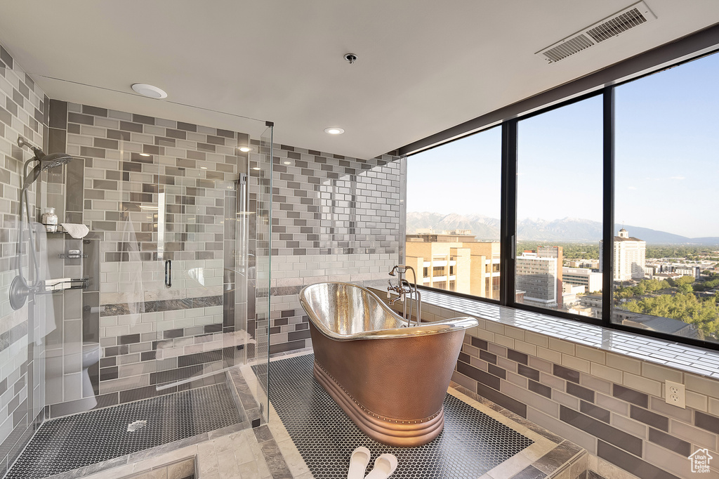 Bathroom with a freestanding tub, a stall shower, a mountain view, tile walls, and recessed lighting