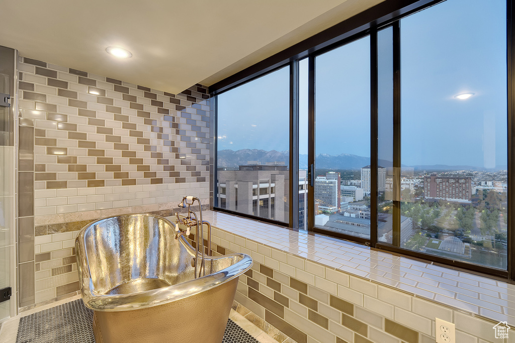 Bathroom with expansive windows, tile walls, tile patterned flooring, a mountain view, and a city view