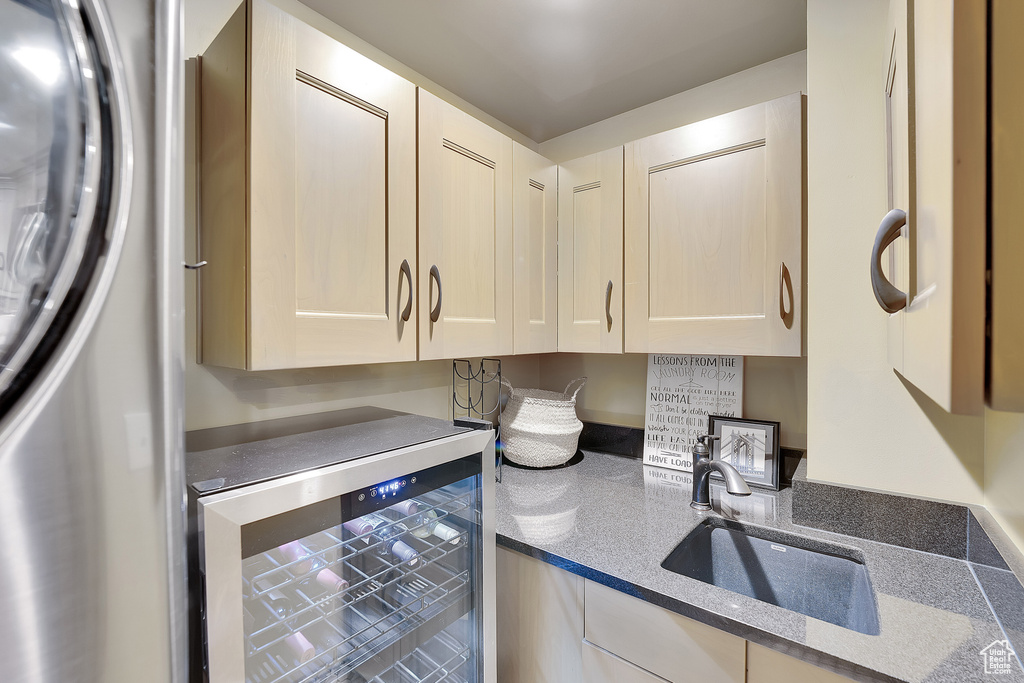 Kitchen featuring beverage cooler, refrigerator, and dark stone counters
