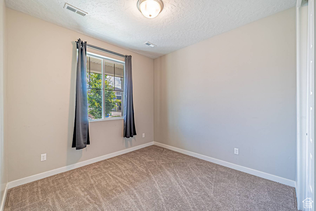 Unfurnished room with carpet floors and a textured ceiling