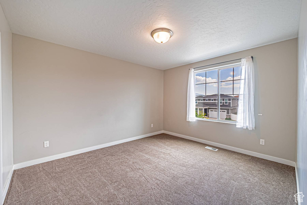 Empty room with a textured ceiling and carpet flooring