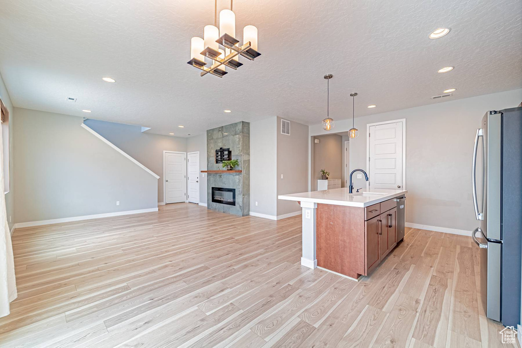 Kitchen with appliances with stainless steel finishes, open floor plan, light wood-style floors, recessed lighting, and an island with sink