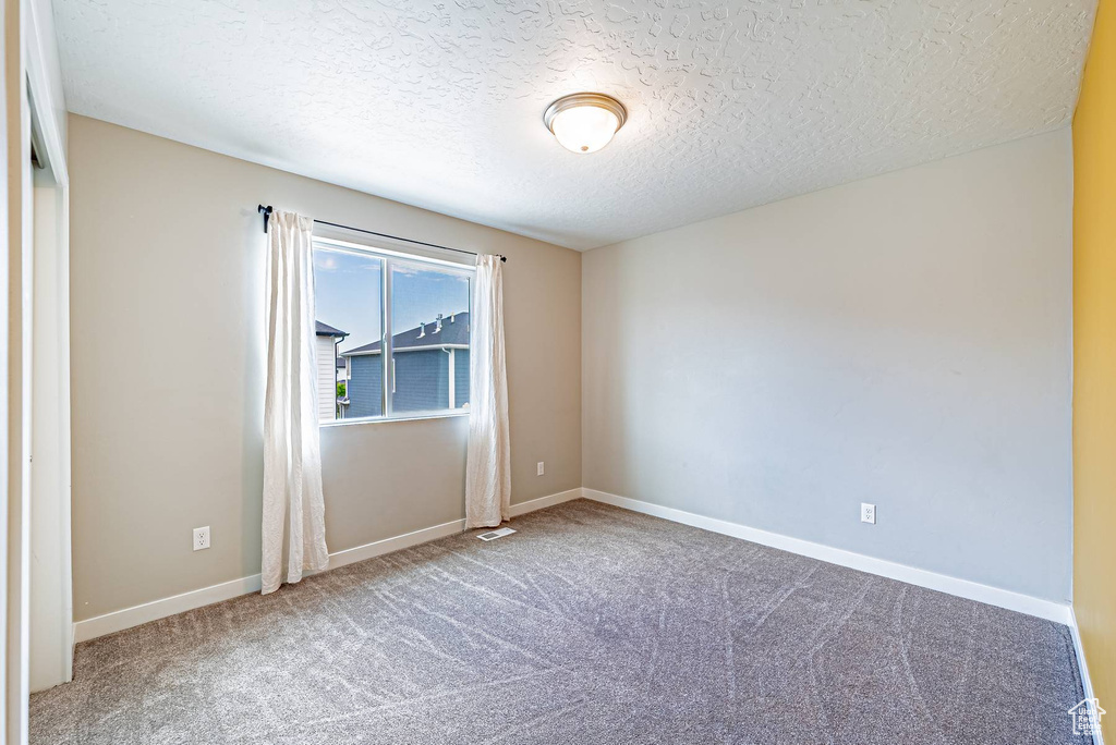 Spare room featuring carpet flooring and a textured ceiling