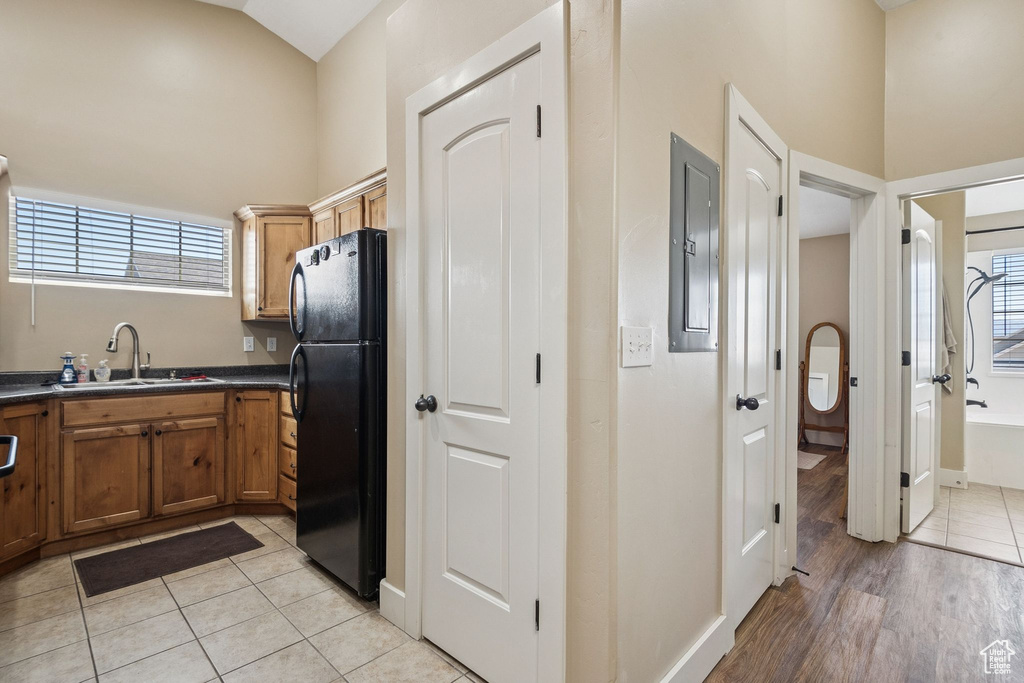Kitchen featuring freestanding refrigerator, dark countertops, high vaulted ceiling, light tile patterned floors, and plenty of natural light