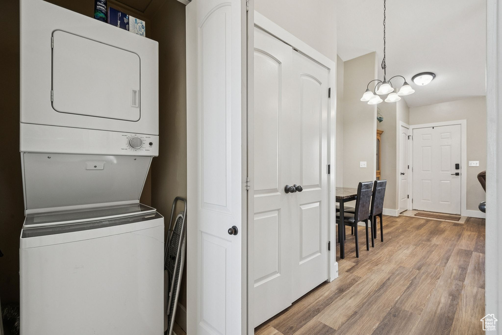 Laundry area featuring estacked washer and dryer, light wood-type flooring, and a chandelier