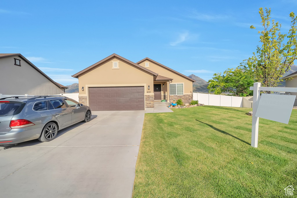 Single story home with concrete driveway, an attached garage, stucco siding, and stone siding