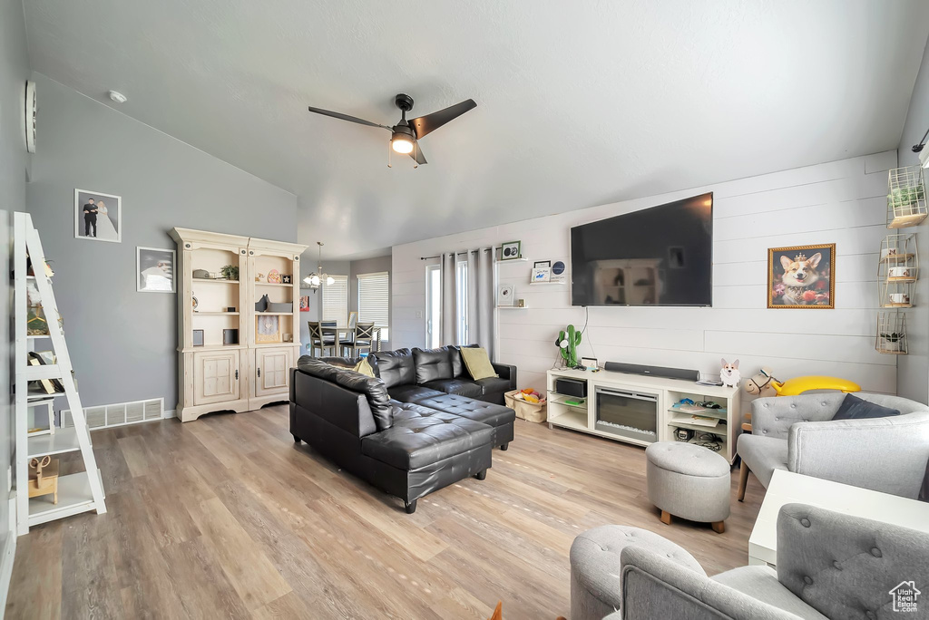 Living room featuring ceiling fan, vaulted ceiling, and light wood-style flooring