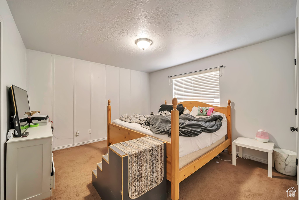 Bedroom featuring light colored carpet and a textured ceiling