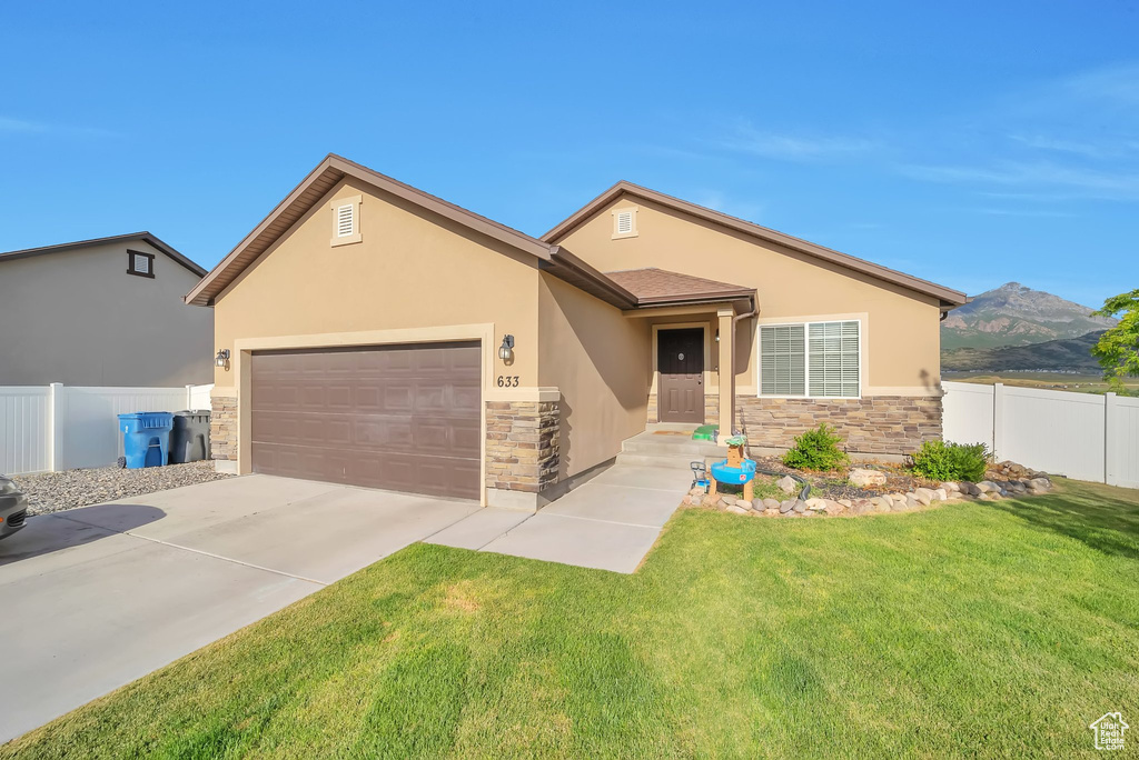 View of front of home with stone siding, stucco siding, an attached garage, driveway, and a mountain view