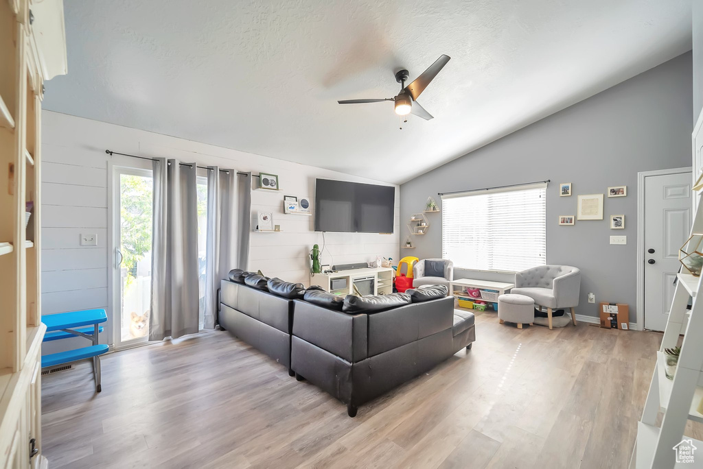 Living room featuring ceiling fan, vaulted ceiling, and light wood-type flooring