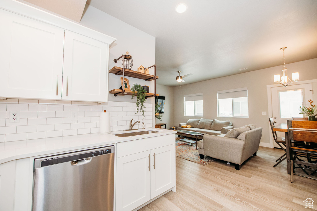Kitchen featuring dishwasher, decorative backsplash, a chandelier, light wood-style flooring, and light countertops
